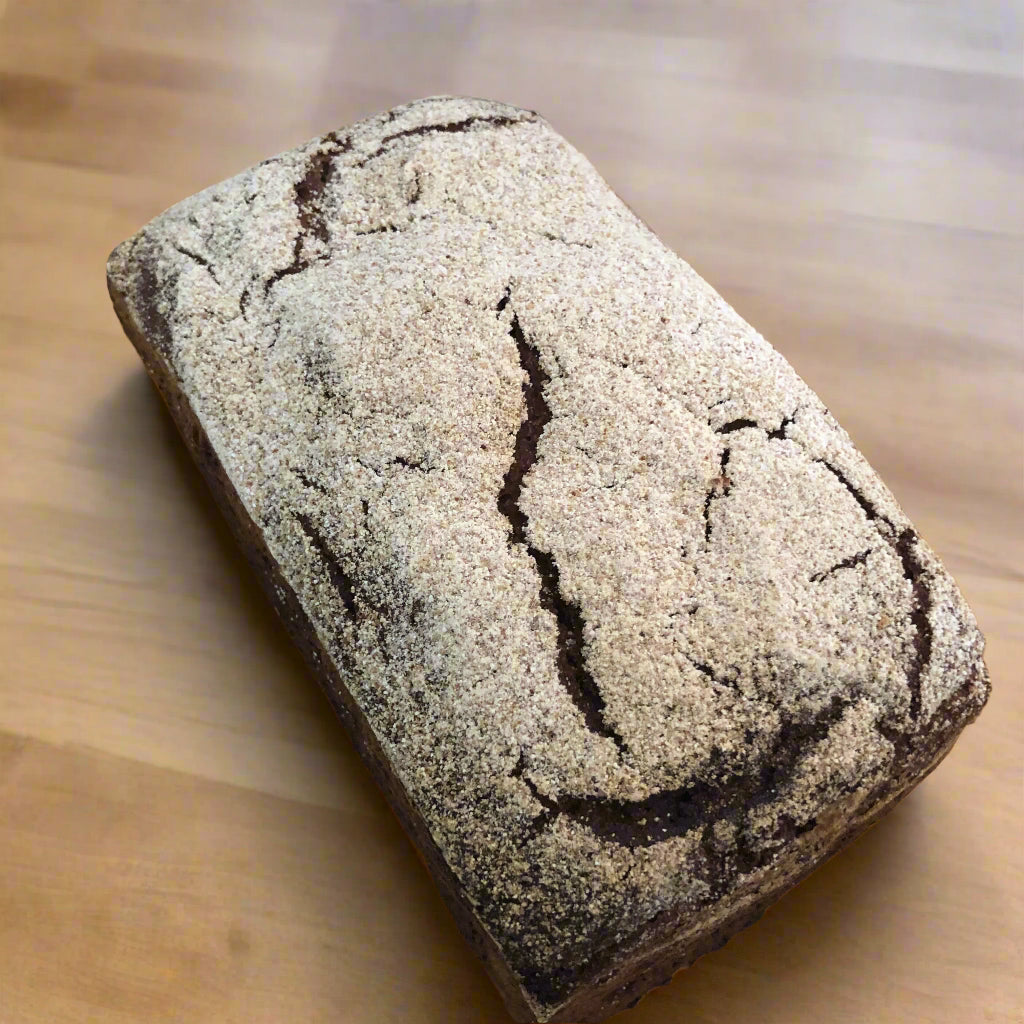 Loaf of rye bread with a crumbly texture on a wooden surface